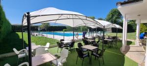 eine Gruppe von Tischen und Stühlen unter einem Pavillon mit Pool in der Unterkunft Casa Rural Alcolea del Pinar in Alcolea del Pinar