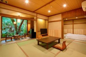 uma sala de estar com uma mesa e uma cama em Mizumari em Kawazu
