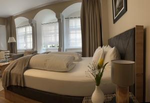 a bedroom with a large white bed with a vase on a table at Hotel Ratsstuben in Lindau