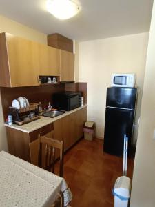 a small kitchen with a black refrigerator and microwave at Апартамент Попов in Sunny Beach