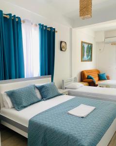 1 dormitorio con 2 camas y cortinas azules en HC Hotel & Suites, en Vlorë