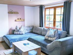 Ferienwohnung Blütenzauber in Idyllischer Lage Nähe Bodensee في Hilzingen: غرفة معيشة مع أريكة زرقاء وطاولة