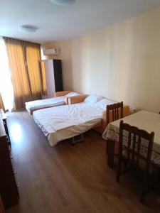 a bedroom with two beds and a table and chairs at Апартамент Попов in Sunny Beach