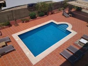 een groot blauw zwembad op een bakstenen patio bij Hostal El Pinar in Montecorto