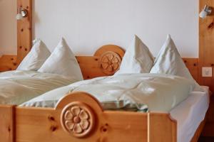 a wooden bed with white sheets and pillows at Hotel Waldhaus in Bettmeralp