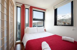 Schlafzimmer mit einem roten und weißen Bett und Fenstern in der Unterkunft Udelka A in Niseko