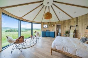 een slaapkamer met een schommelbed en een groot raam bij The Roundhouses in Alnwick