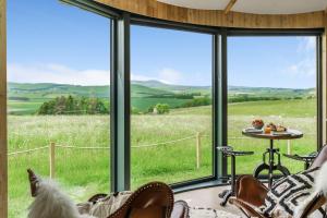 uma vista para um campo a partir de um quarto com janelas em The Roundhouses em Alnwick