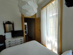 a bedroom with a bed and a television and a window at A Vianesa - Guest House in Viana do Castelo