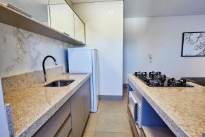 a kitchen with a sink and a stove at Ap 403 c/ 2 Qts, sacada, garagem e A/C in Maringá