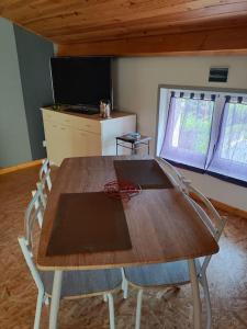 a wooden table and chairs in a room with a television at Chez Serge et Annie in Polignac +4 photos