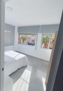 a white bedroom with a bed and two windows at Paradise Sol Apartamento en Los Alcázares in Los Alcázares
