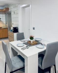 a kitchen with a white table with chairs and plates at Paradise Sol Apartamento en Los Alcázares in Los Alcázares