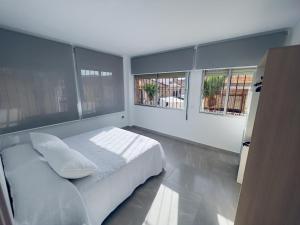 a bedroom with a white bed and two windows at Paradise Sol Apartamento en Los Alcázares in Los Alcázares