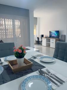 a white table with plates and a vase of flowers on it at Paradise Sol Apartamento en Los Alcázares in Los Alcázares