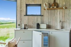 uma cozinha com armários brancos e uma janela em The Roundhouses em Alnwick