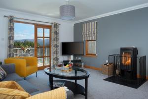 a living room with a couch and a table at Snowmass Lodge - hot tub in Aviemore in Aviemore