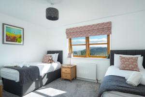 a bedroom with two beds and a window at Snowmass Lodge - hot tub in Aviemore in Aviemore