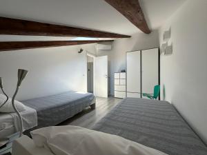 Un dormitorio blanco con 2 camas y una silla verde. en CasaNico, en Trieste