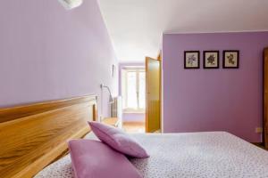 阿西西的住宿－伊爾城堡農莊旅館，一间卧室设有紫色的墙壁和一张带枕头的床