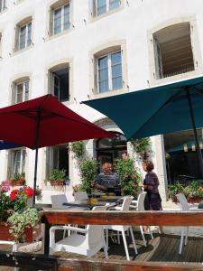 a couple of people sitting at a table with umbrellas at Auberge d antan du Lion d Or in Le Locle