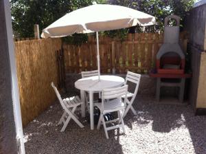 a table and chairs with an umbrella and a grill at U Paesu in Zonza