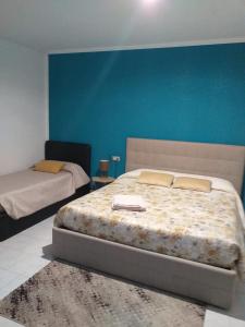 een slaapkamer met 2 bedden en een blauwe muur bij Affittacamere da Arianna in Porto Torres