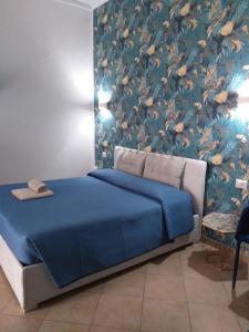 a bedroom with a blue bed with a floral wallpaper at Affittacamere da Arianna in Porto Torres
