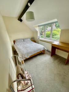 1 dormitorio con cama, escritorio y ventana en Charming just renovated 2 bed cottage in the centre of village, en Hartford