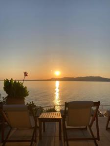 a sunset over the water with two chairs and a table at Rosys Little Village in Skala