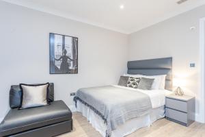 - une chambre avec un lit et une chaise dans l'établissement Cleveland Residences Chelsea, à Londres