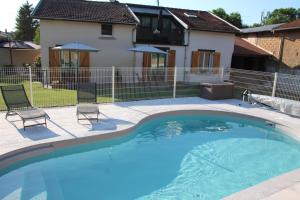 a swimming pool with two chairs and a house at le clos des flâneries 
