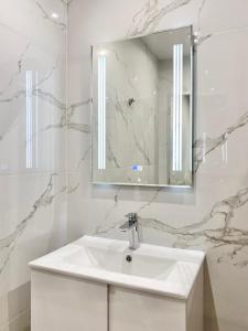 La salle de bains blanche est pourvue d'un lavabo et d'un miroir. dans l'établissement Comfort & Classy 1Bed Аpartment for 4 Guests, à Plovdiv
