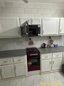 a kitchen with white cabinets and a stove and microwave at Ifson Home_1 in Kankamsen