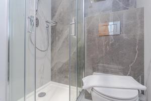 a bathroom with a toilet and a glass shower at Cleveland Residences Chelsea in London