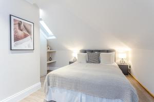 a white bedroom with a bed and two lamps at Cleveland Residences Chelsea in London