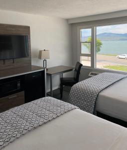 ein Hotelzimmer mit 2 Betten, einem Schreibtisch und einem TV in der Unterkunft Americas Best Value Inn Polson in Polson