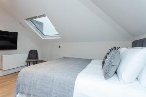 a bedroom with a large bed with a skylight at Cleveland Residences Chelsea in London