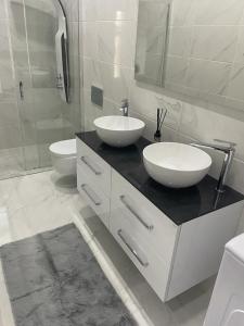 a white bathroom with two sinks and a mirror at Seafront Apartment in Skala Mistegnon