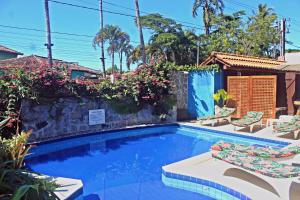 una piscina con tumbonas y flores en Pousada Fragata - Arraial D Ajuda - Melhor Localização e Atendimento, en Arraial d'Ajuda