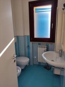 a bathroom with a toilet and a sink and a window at A casa di Milena in Porto Recanati