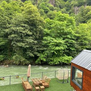 a patio with a table and chairs next to a river at Butka tiny house in Ardeşen