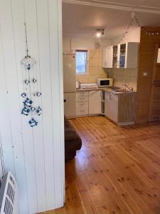 a kitchen with white cabinets and a wooden floor at Domek letniskowy Pogorzelica in Pogorzelica