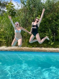 dos mujeres saltando al aire cerca de una piscina en Panorama udsigt og pool, en Ålsgårde