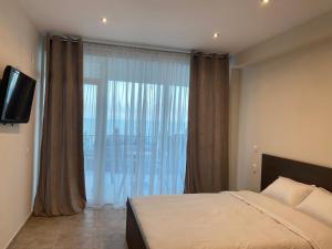 a bedroom with a bed and a large window at Lemon in Costinesti