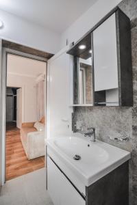 a bathroom with a white sink and a living room at Luka Apartments in Sarandë