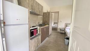 a kitchen with a white refrigerator and a sink at Kalouda Rooms in Paralía Skotínis