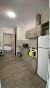 a kitchen with a white refrigerator and a room with a bed at Kalouda Rooms in Paralía Skotínis
