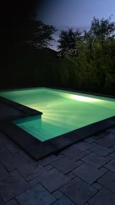 Panorama udsigt og pool في Ålsgårde: حمام سباحة مع إضاءة خضراء في الليل
