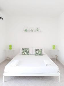białe łóżko w białym pokoju z dwoma stołami w obiekcie Rosso di Sera Loft w mieście Menfi
